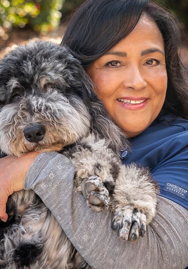 woman holding and hugging black and gray dog